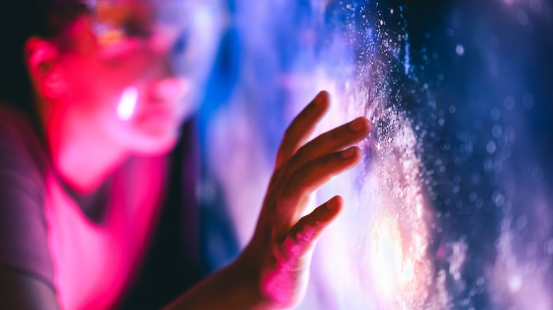 A face and hand touching an interactive display.