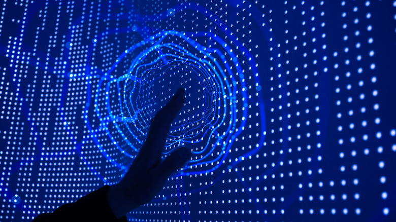 A silhouetted hand touching an interactive display.