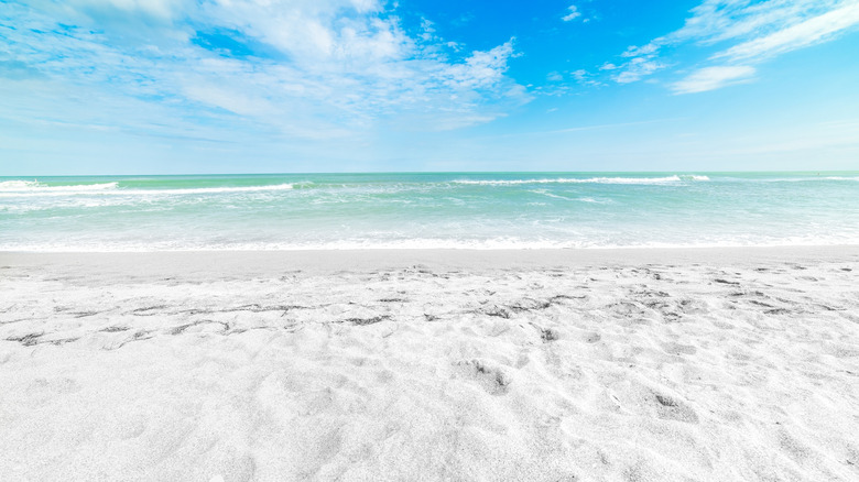 Beautiful blue water with a white sand beach in the front and clear blue skies