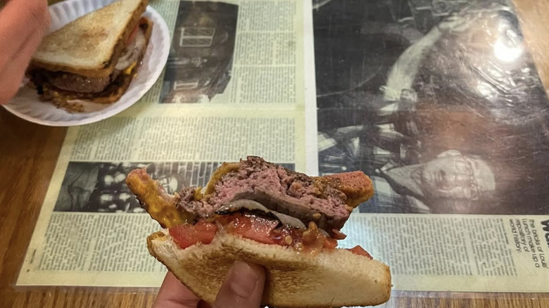 Hamburger sandwich held by customer at Louis' Lunch in New Haven, CT