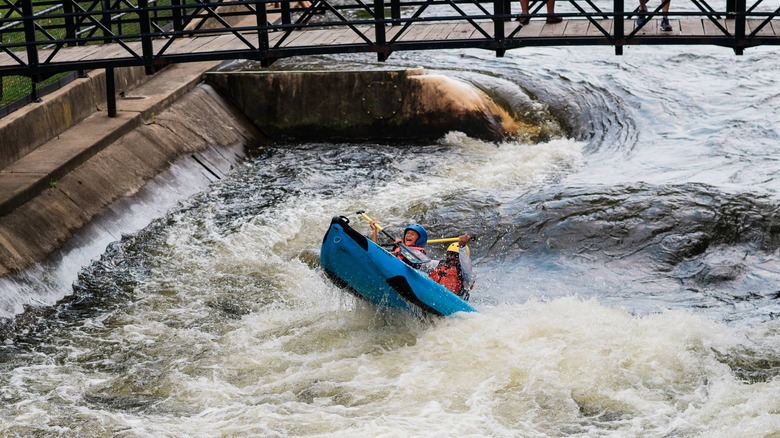 A two person raft tilts upwards on a gnarly section of the East Race Waterway