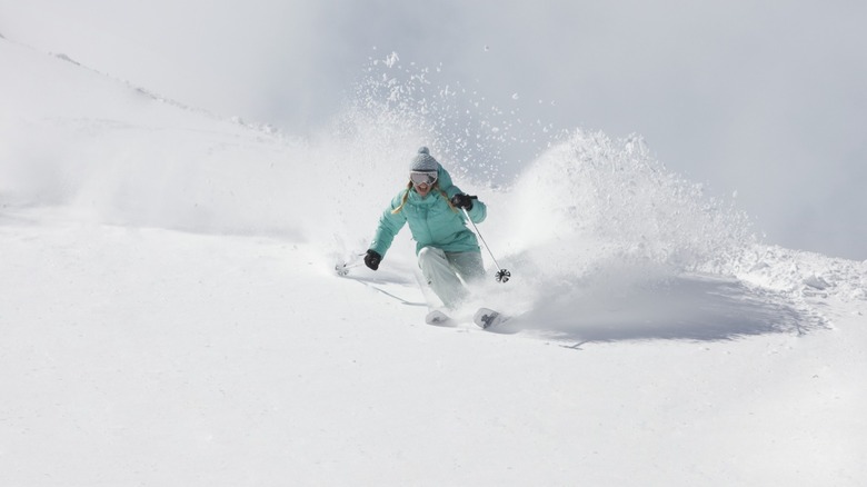 Man skiing down mountain of powdery snow.