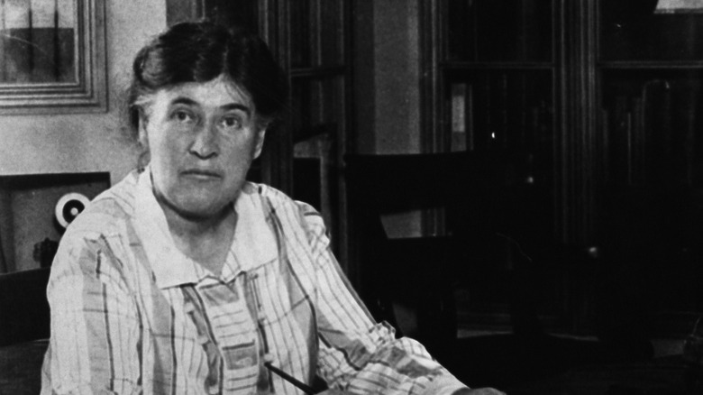 Black and white historical photo of Willa Cather woman writer at desk looking into camera