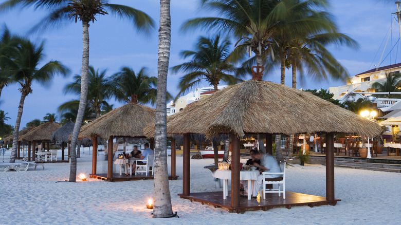 People eating under huts at Eagle Beach