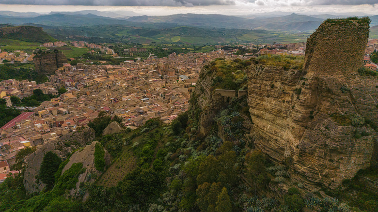 Red roofs of small hillside town surrounded by green trees and rock formations