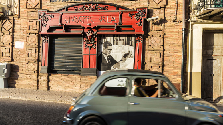 Old-fashioned pharmacy in Corleone with vintage Italian car driving past