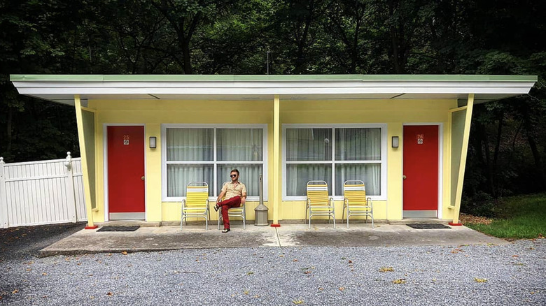 Man sitting outside retro cottages at the Koolwink Motel, Romney, WV