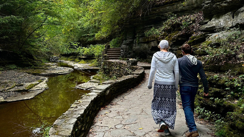 Two people walking along a stone trail at Watkins Glen State Park in New York