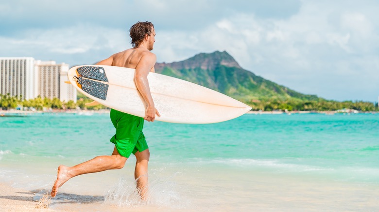 Surfer entering the water in Waikiki with Diamond Head in the background