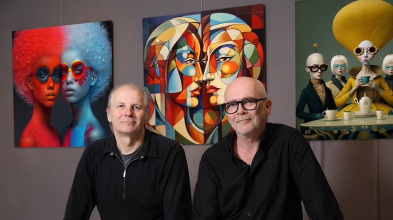 Constant Brinkman and Paul Bookelman, co-founders of Dead End Gallery, sitting in front of three AI-generated images displayed in their gallery in Amsterdam