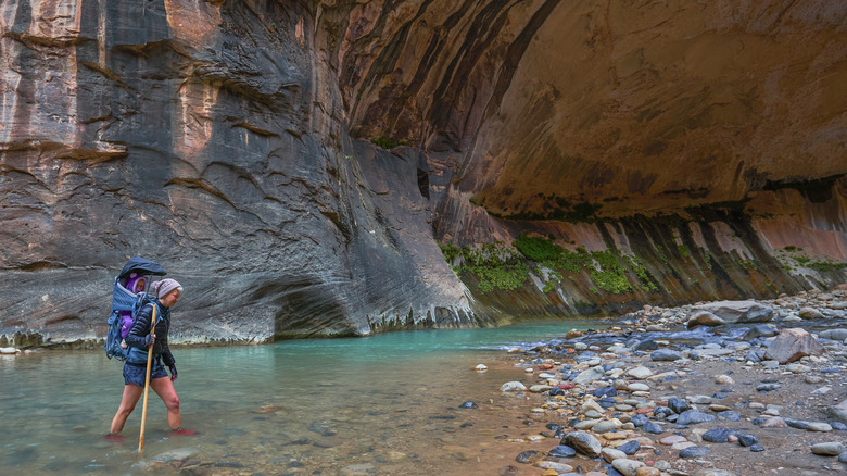 A person with a backpack hiking The Narrows in Zion National Park in Utah