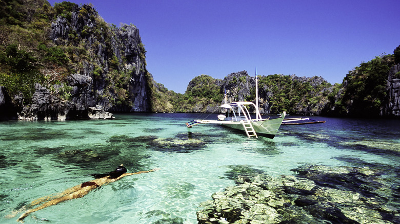 Boat and snorkeler in a lagoon near Miniloc Island, Philippines