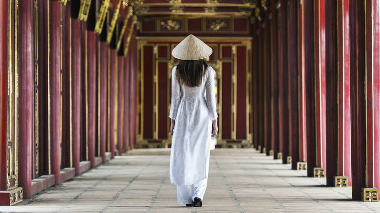 A woman walking down the red corridor at the Forbidden Purple Palace in Hue, Vietnam