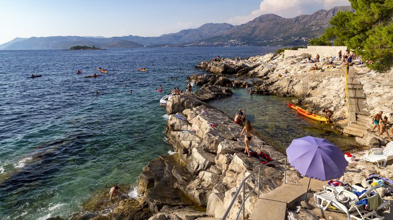 People sunbathing on the rocks on a beach in Cavtat, Croatia