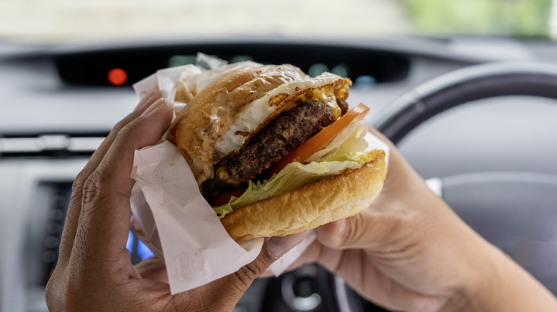 Person holding burger in car