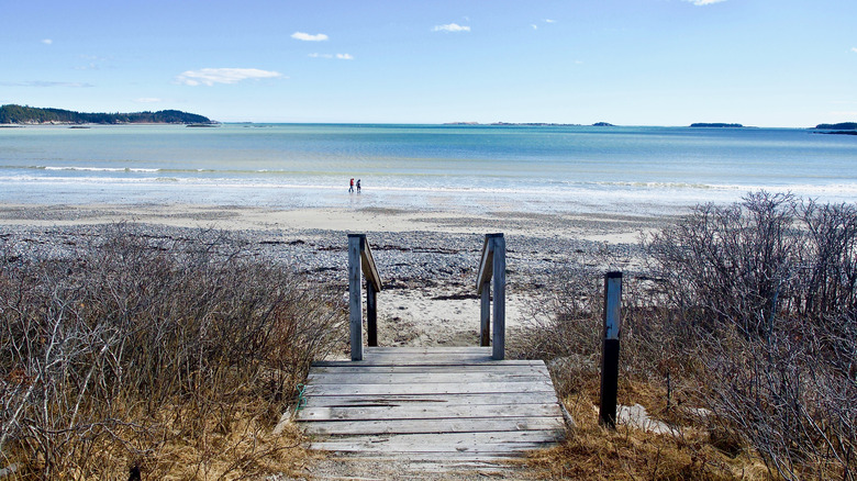 Couple walks by entrance to beach at Roque Bluffs State Park