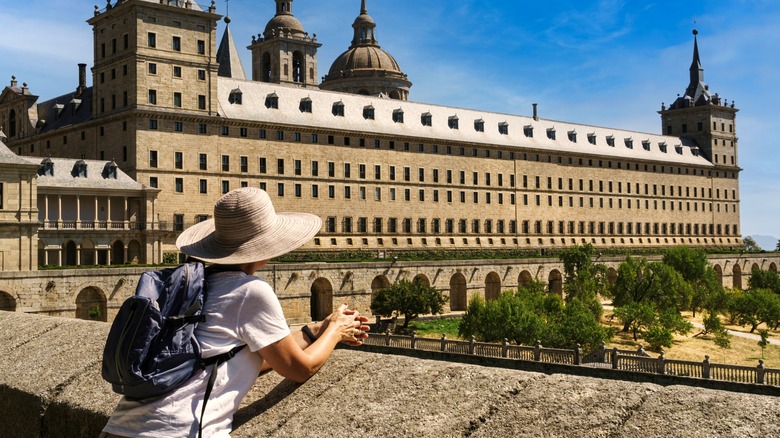 Woman with hat and backpack looking over garden