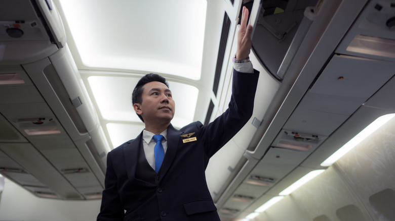 Flight attendant closing overhead bin