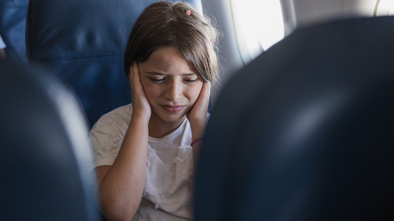 Girl covering ears on plane