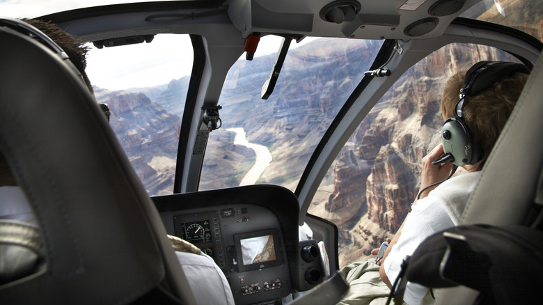 Interior of a helicopter flying over the Grand Canyon with view of passenger wearing ear protectors.