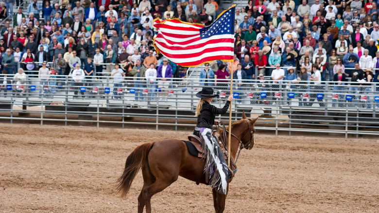 A cowgirl holds an American Flag at the Rodeo