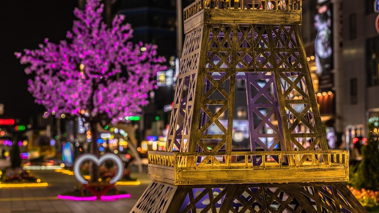 small Eiffel Tower replica at night in front of a purple lit tree