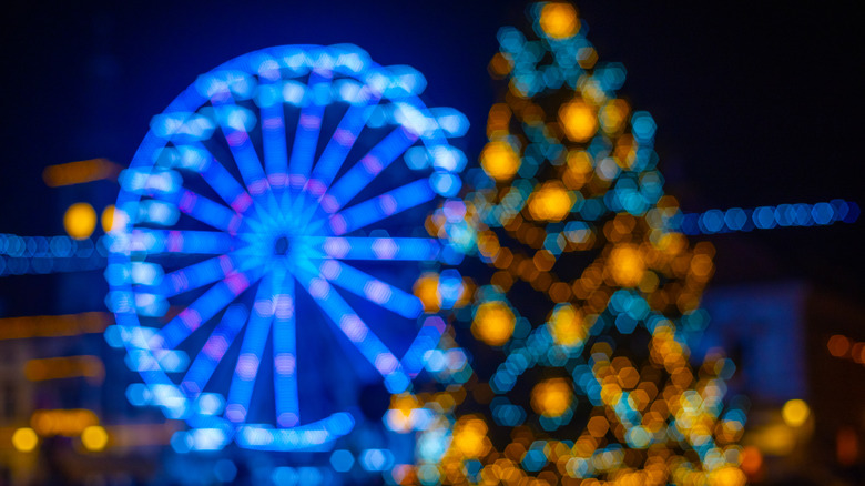 A Christmas tree in front of a lit up Ferris wheel