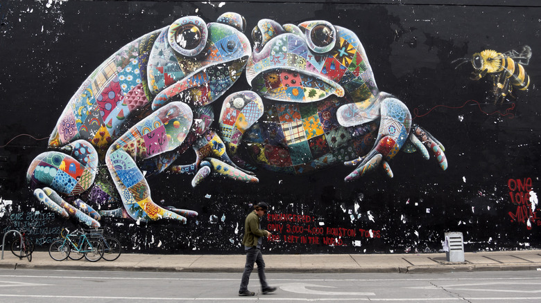 A man walking past a colorful street mural of frogs in Austin, Texas