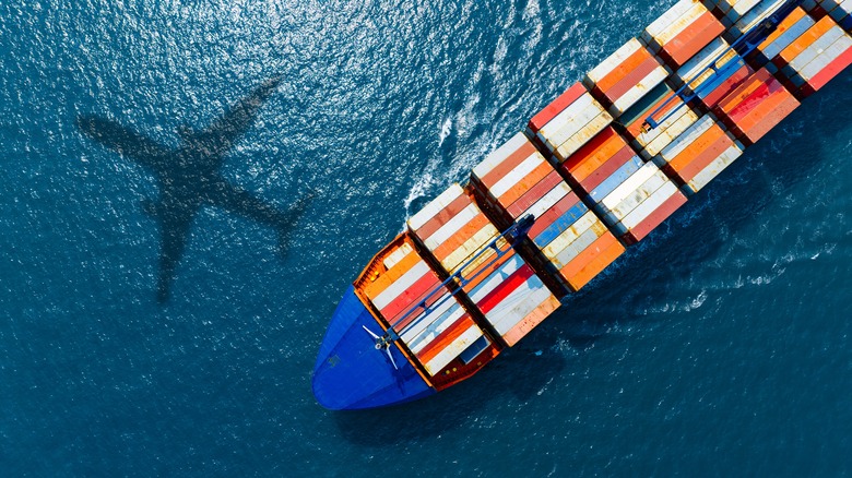 A cargo ship and the shadow of a plane on the water