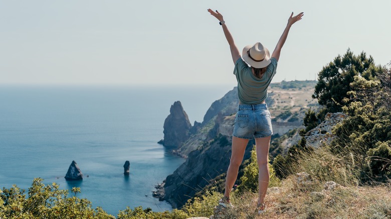 Woman with arms up overlooking sea