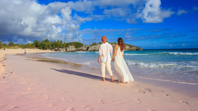 couple strolling pink sand beach