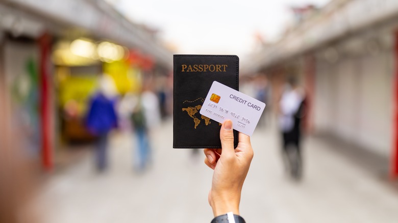 hand holding a passport and credit card