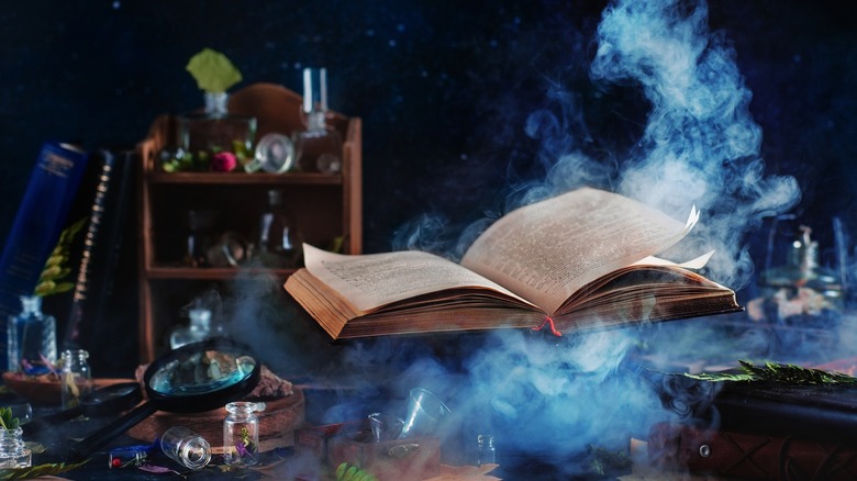 levitating book above a table of potions and magic equiment