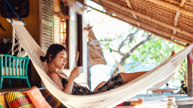 A woman at a retreat relaxing in a hammock while holding a cup