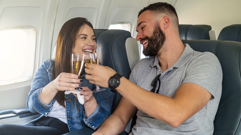 A couple toasting drinks inside a plane