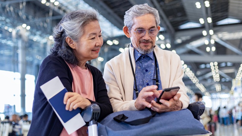 Couple at the airport: One has a paper boarding pass and the other has it on a phone