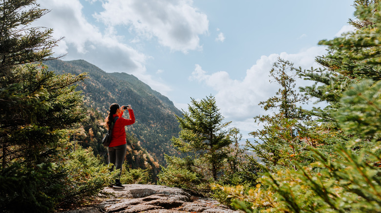 A hiker takes a photo of the Adirondack mountains in New York