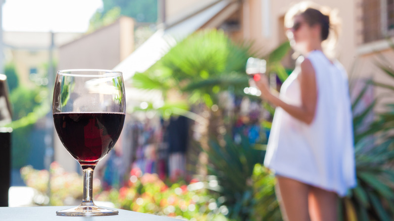 A glass of red Bardolino wine with a woman and the town in the background