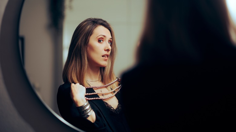 woman looking at necklace in mirror