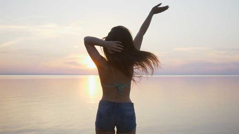 A woman waves on a beach