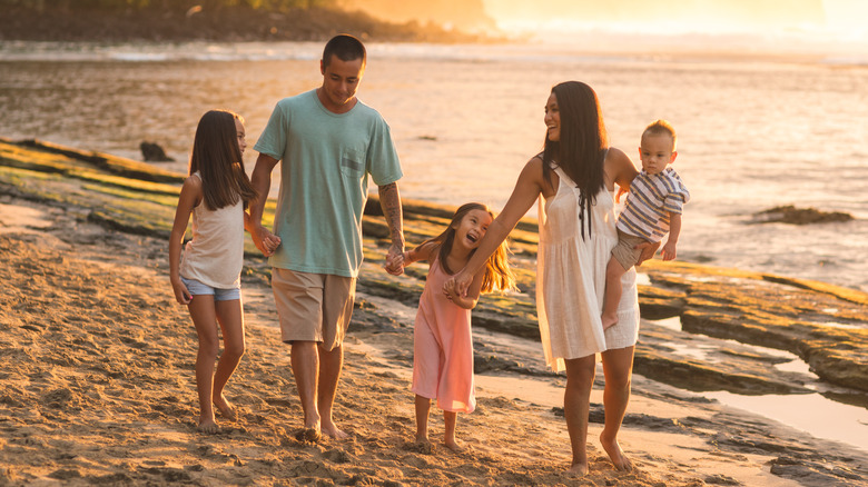 Family walks on beach at sunset