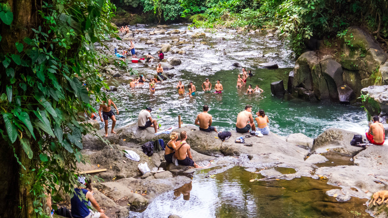 People enjoying swinging El Salto swimming hole in Costa Rica