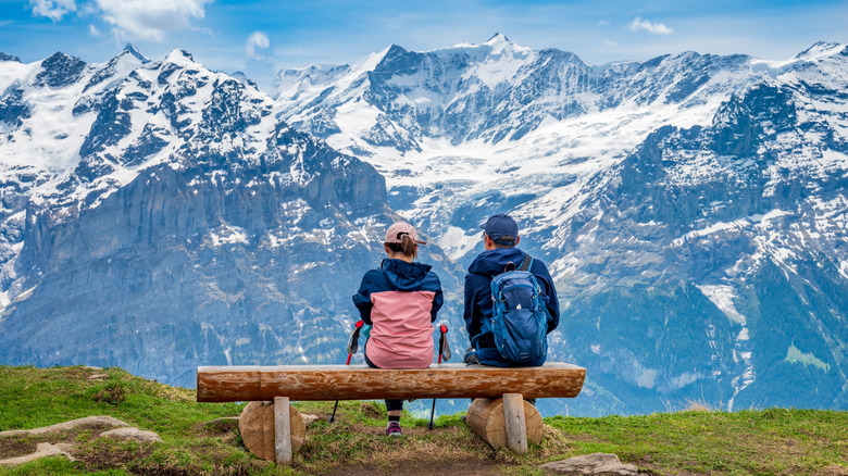 Couple sitting on bench amidst Alps