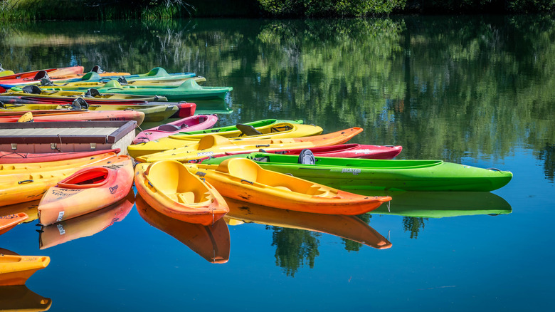 Scattered canoes of different colors on a still river