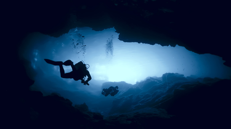 Divers swimming through a cave