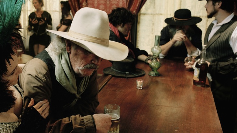 Cowboy in a five gallon hat drinks a beer at a saloon