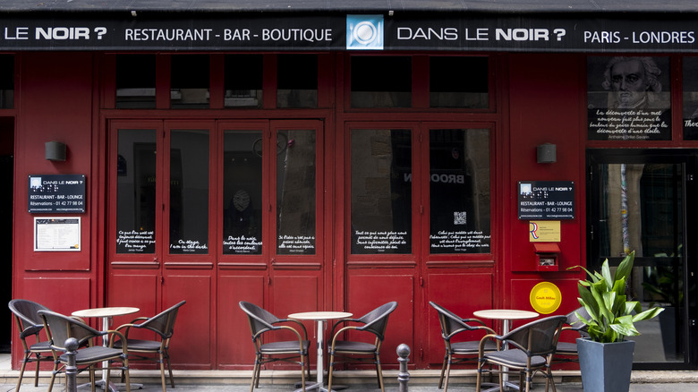 The red facade and outside terrace of Dans le Noir ? restaurant in Paris