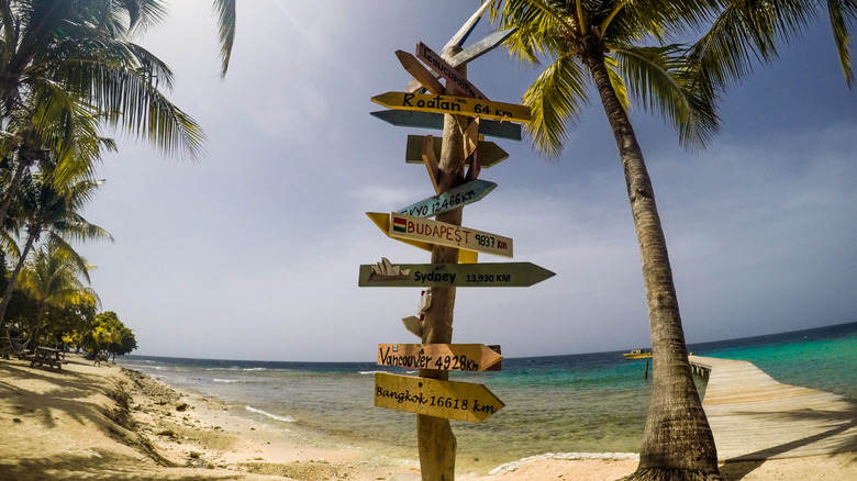 Colorful distance sign to various parts of the world on Utila beach