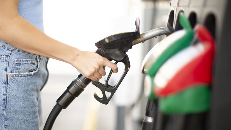 Woman taking a gas nozzle from a gas station pump