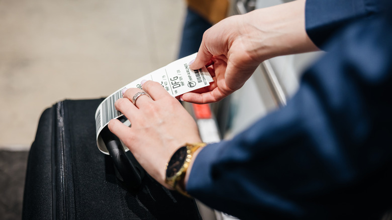 Person putting tag on luggage